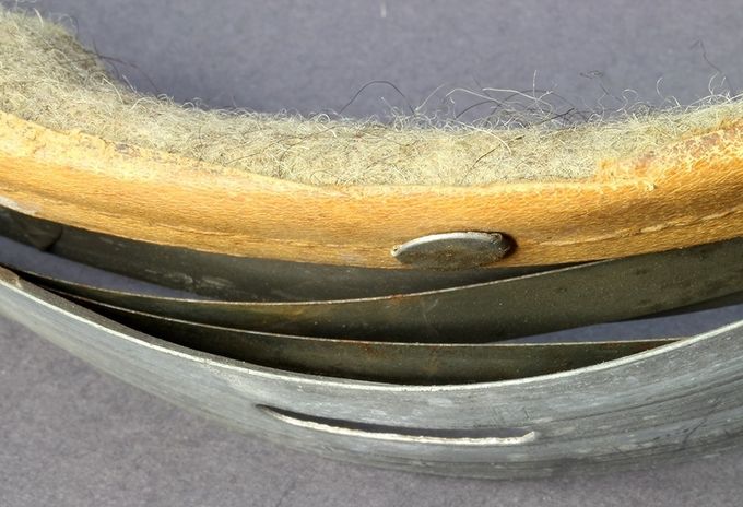 Steel band with green painted steel leaf springs. This leather has been cut off (probably postwar) and you can see the wool strip.