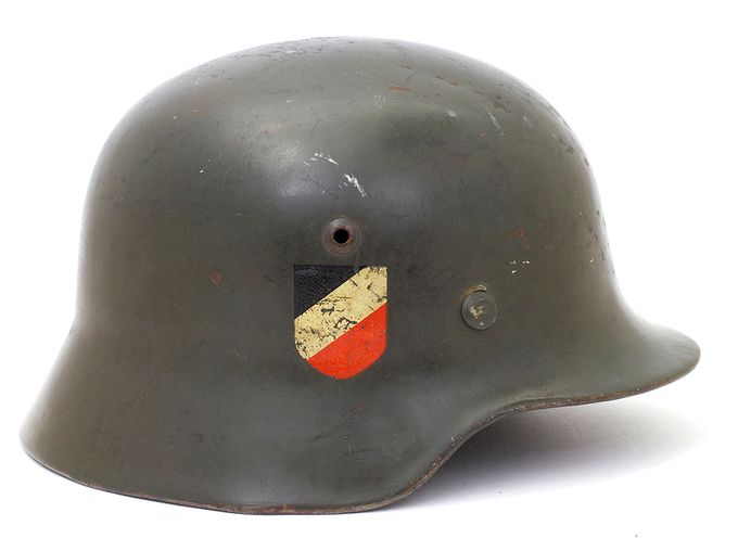 M35, seen from the right. What characterizes this side of the shell is the national shield or tricolor which has the color of black, white and red, representing the German national flag during the war. Vent and rivet on the right side are located symmetrically relative to the left side. The vent hole contains a grommet which is a separate part that is pressed into an opening in the shell during the manufacturing process. The early rivets of the M35 were manufactured of brass and zinc-coated by galvanization. Aluminum rivets were also used but in small numbers.
